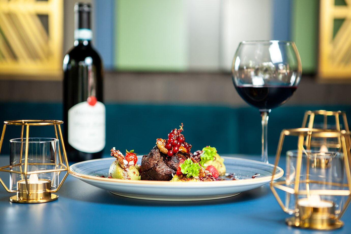 Plated gourmet meal with steak and vegetables, paired with red wine, set on an elegant restaurant table.