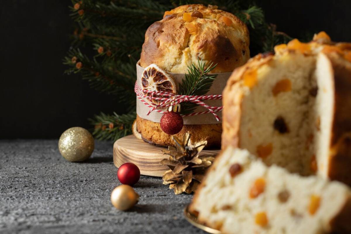 A festive Panettone adorned with a decorative twine and Christmas ornaments, set against a dark backdrop with a pine branch.