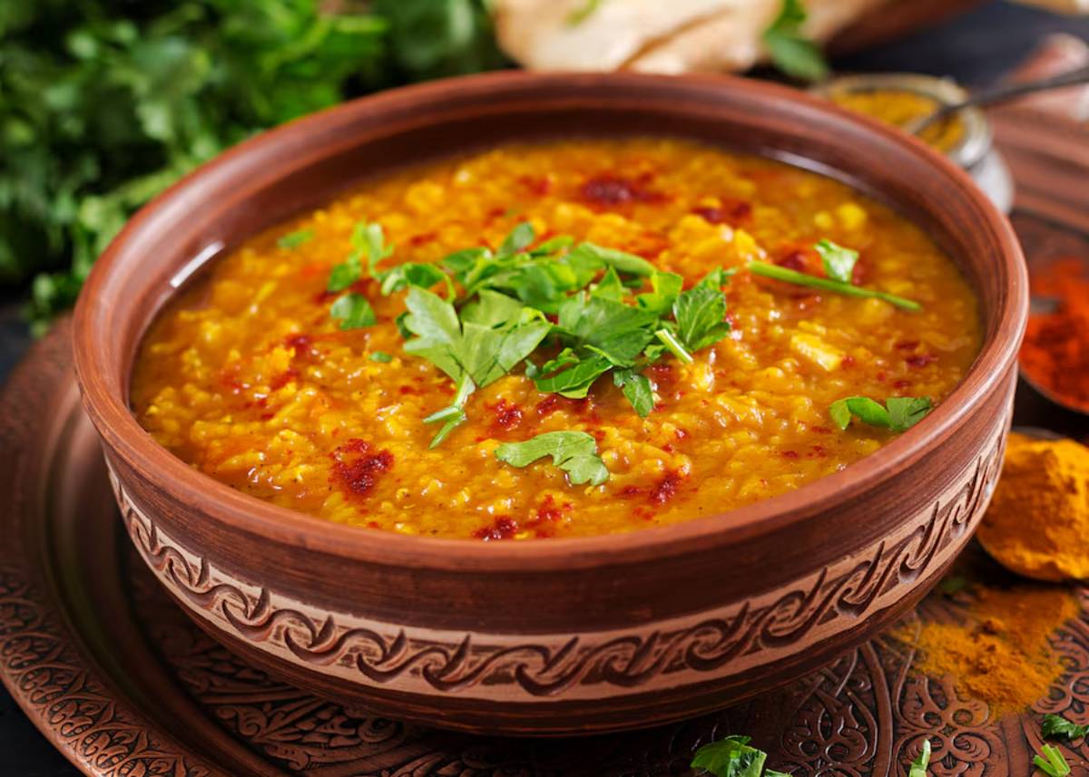 A traditional Indian dal served in a decorative clay bowl, garnished with fresh cilantro.