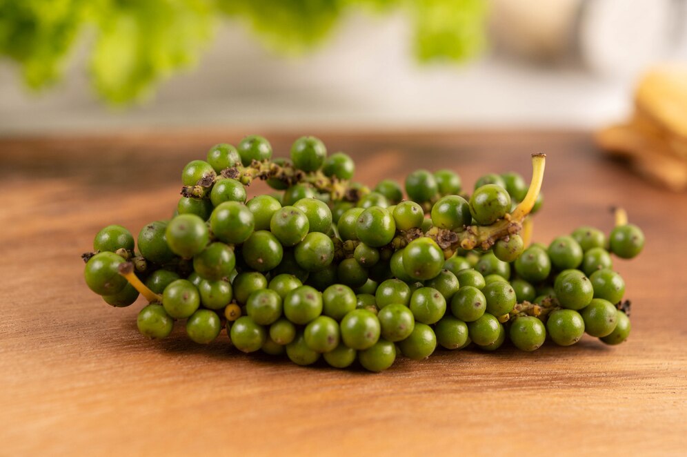 Cluster of unripe green grapes on a wooden table, with soft-focus background.