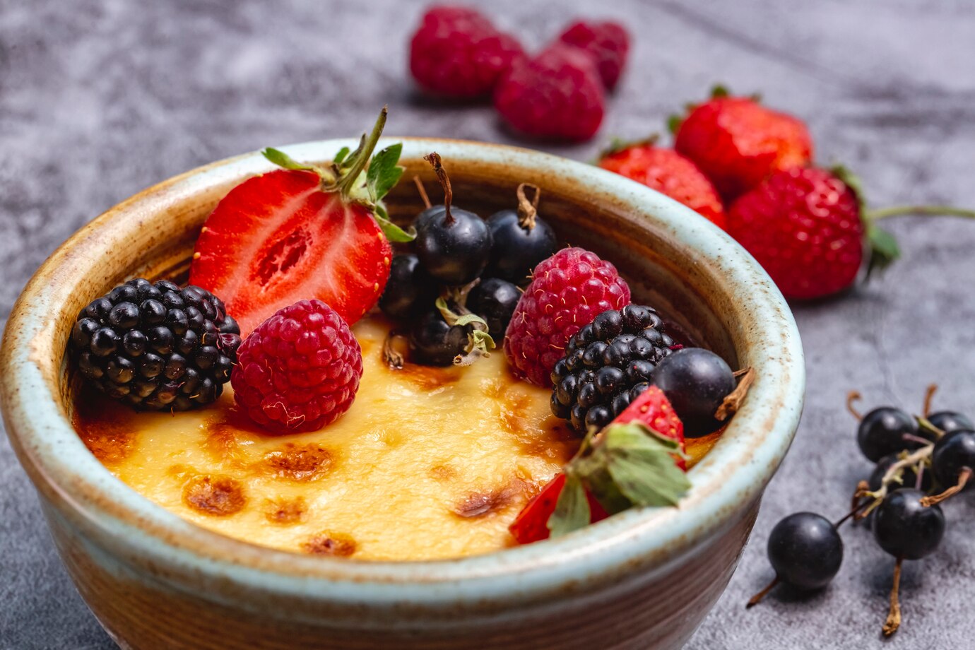 A creamy dessert topped with a variety of fresh berries, including strawberries