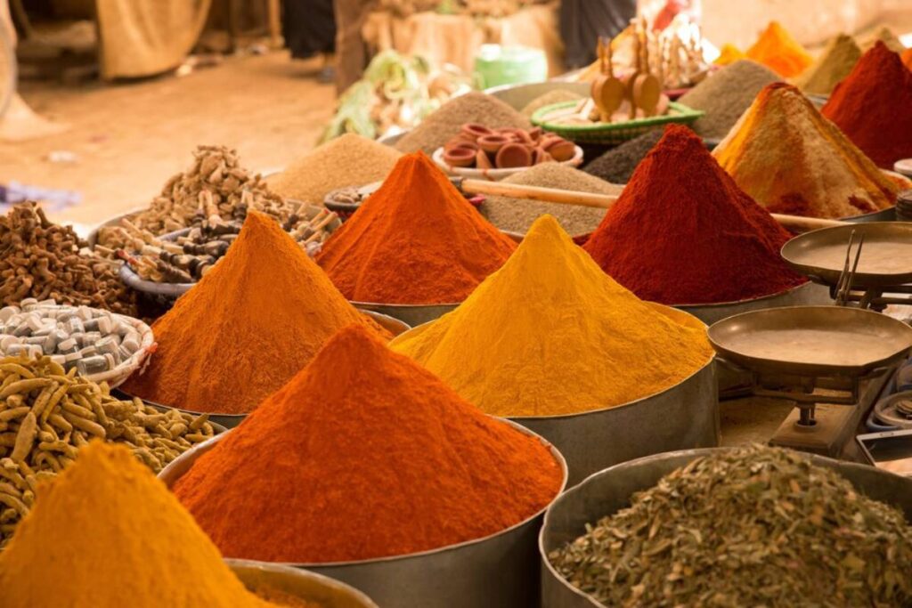 Colorful mounds of various spices displayed in an open market setting.
