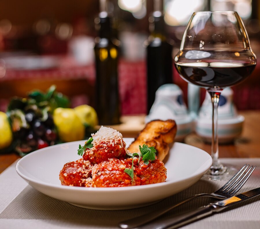 A plate of three meatballs in marinara, garnished with parsley and cheese